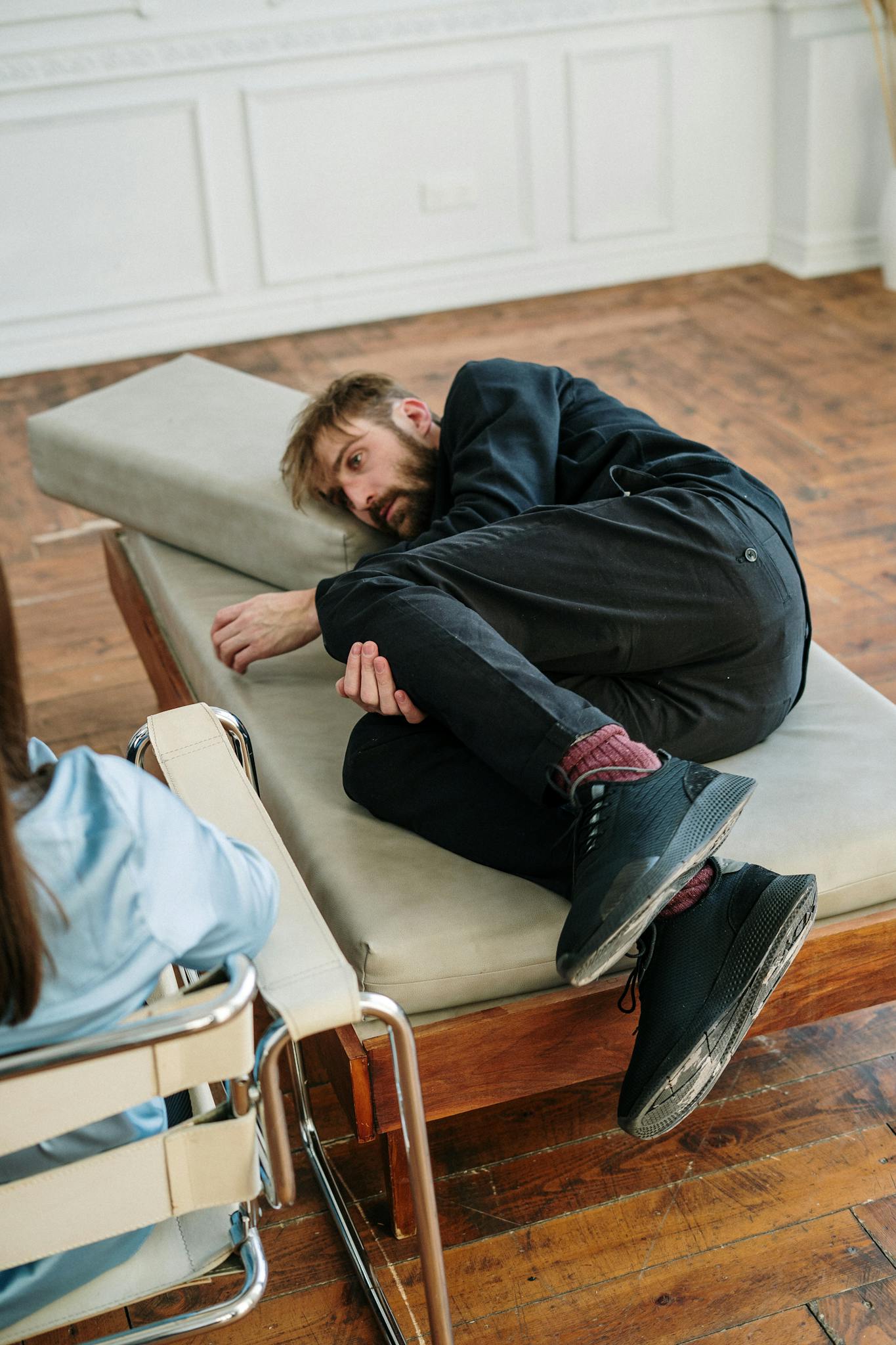 A man in a therapy session lies on a couch, looking contemplative and introspective.